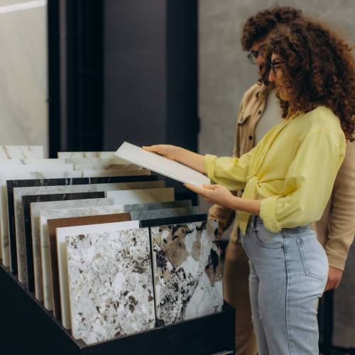 Young couple selecting new ceramic tiles for home renovation. They are standing near a display choosing between patterns
